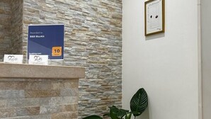 A reception area with a stone wall, a framed certificate on the wall, and a potted plant. - B&B MarAlè (Porto Cesareo)