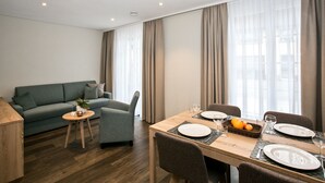 Une chambre d’hôtel moderne avec un coin repas, un canapé et une petite table agrémentée d’une plante.