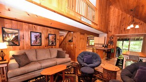 Un intérieur en bois comprenant un canapé, des fauteuils, un coin repas et un escalier.