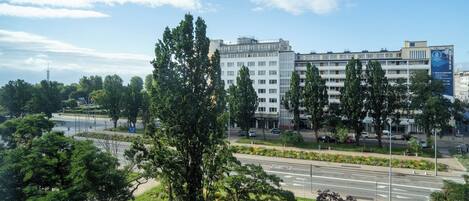 A multi-story building with a modern architectural design, surrounded by greenery and a clear sky.