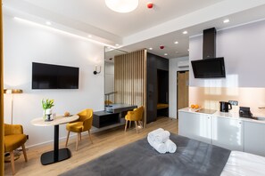Una habitación de hotel moderna con cama, escritorio, silla, televisor y kitchenette.