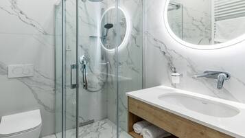 Ein modernes Badezimmer mit einer Duschkabine aus Glas, einem weißen Waschbecken und einem Boden mit Marmorfliesen.