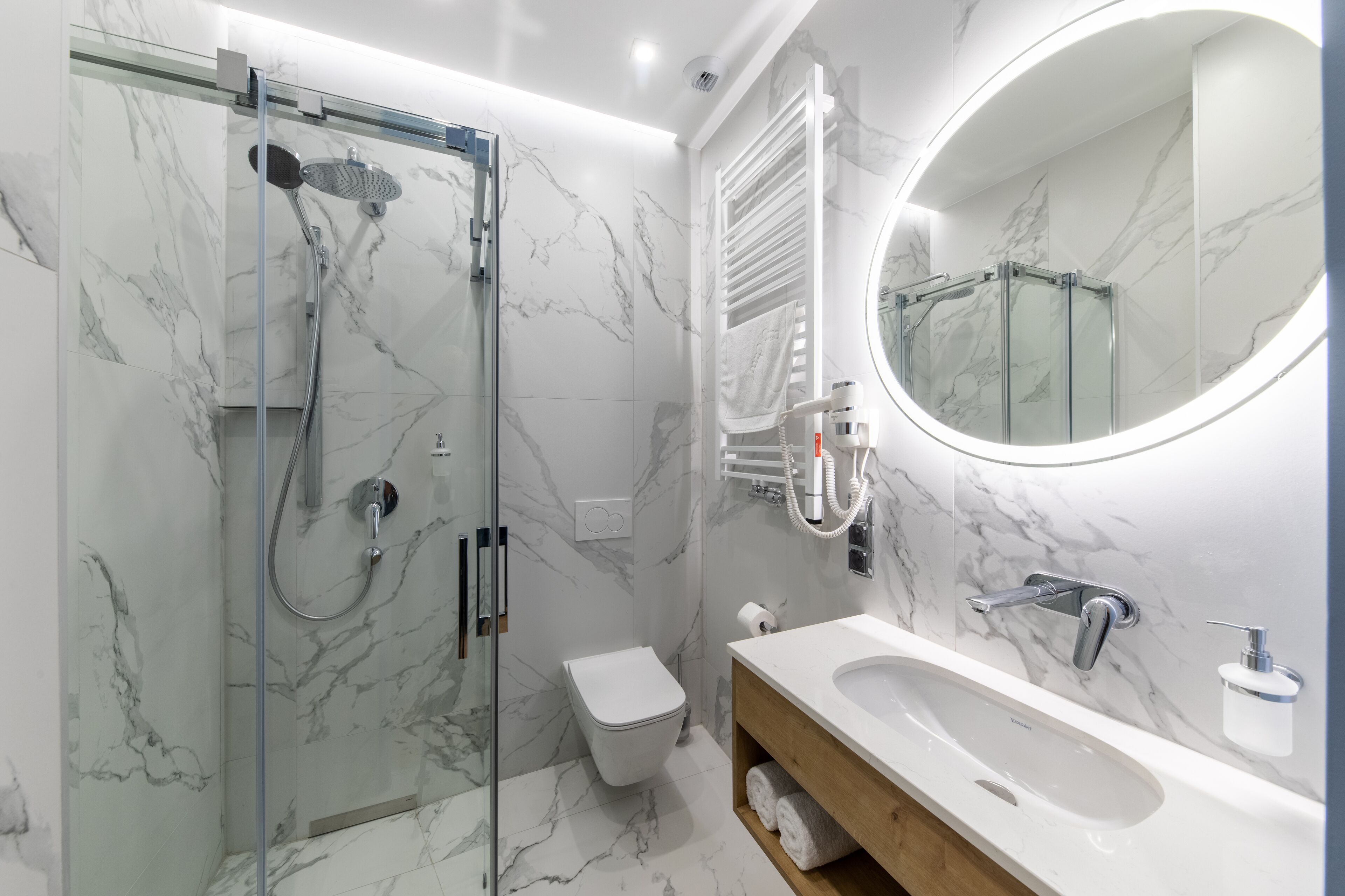 A modern bathroom with a glass-enclosed shower, a white toilet, and a vanity with a large mirror.
