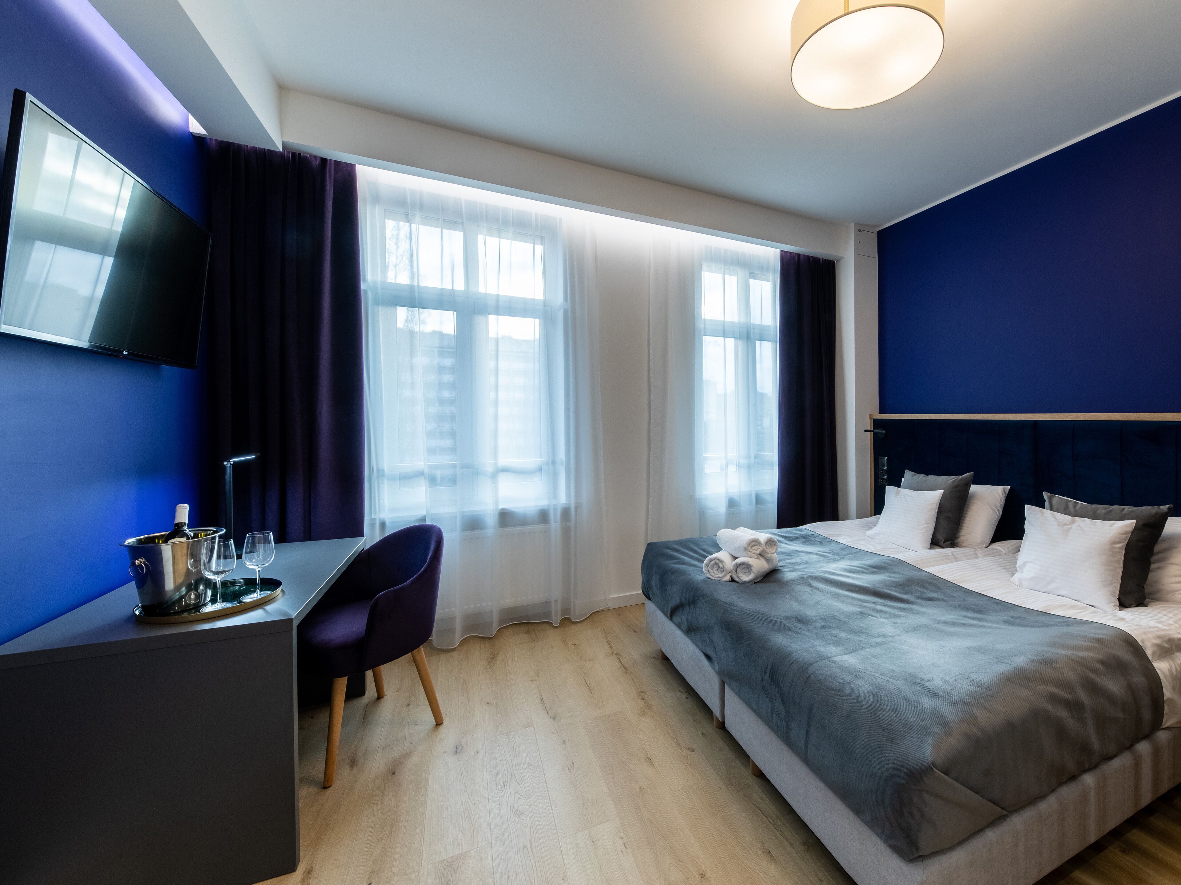 A modern hotel room with a bed, a desk, and a TV.