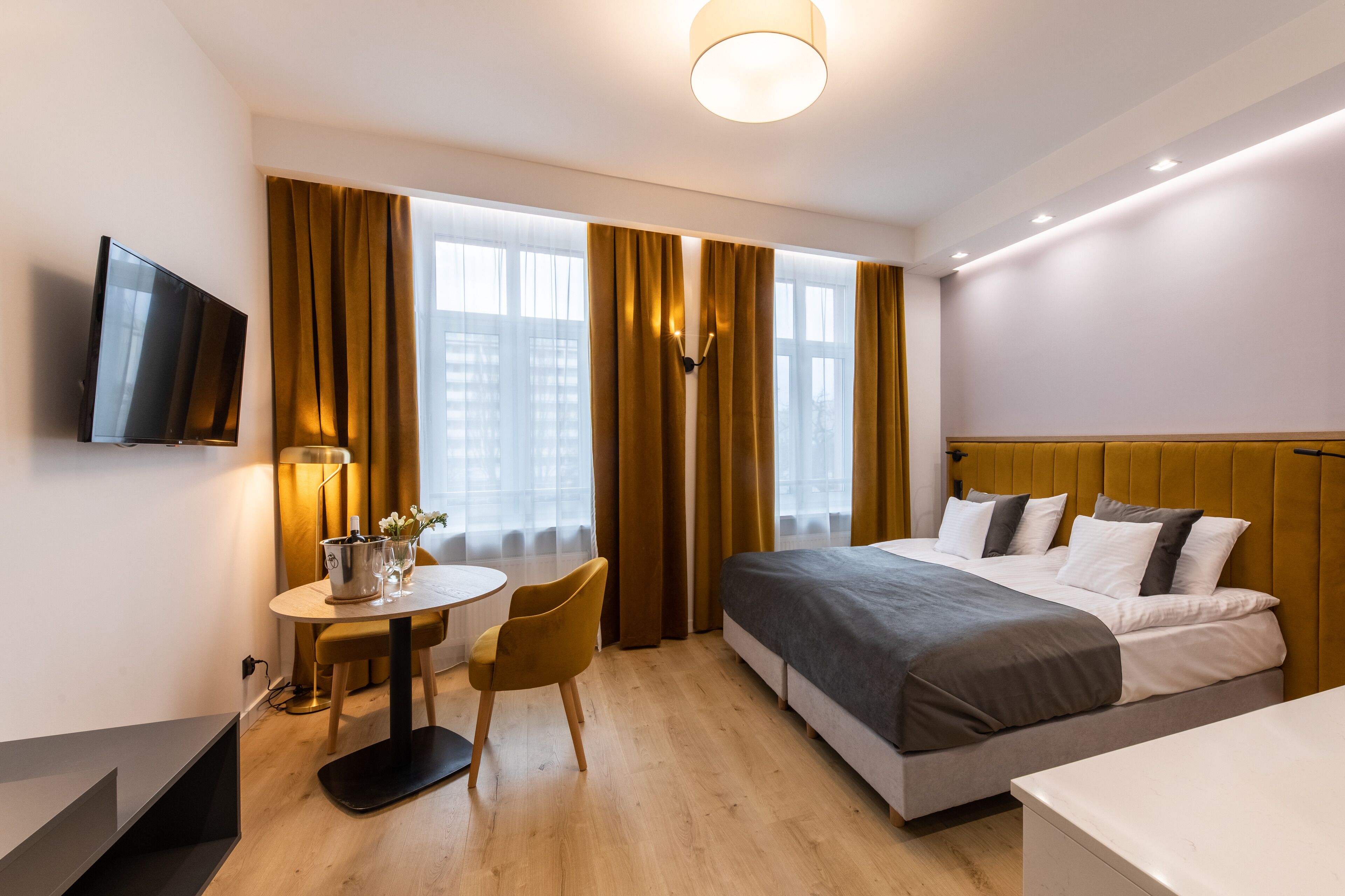A modern hotel room with a bed, a desk, a chair, and a television.
