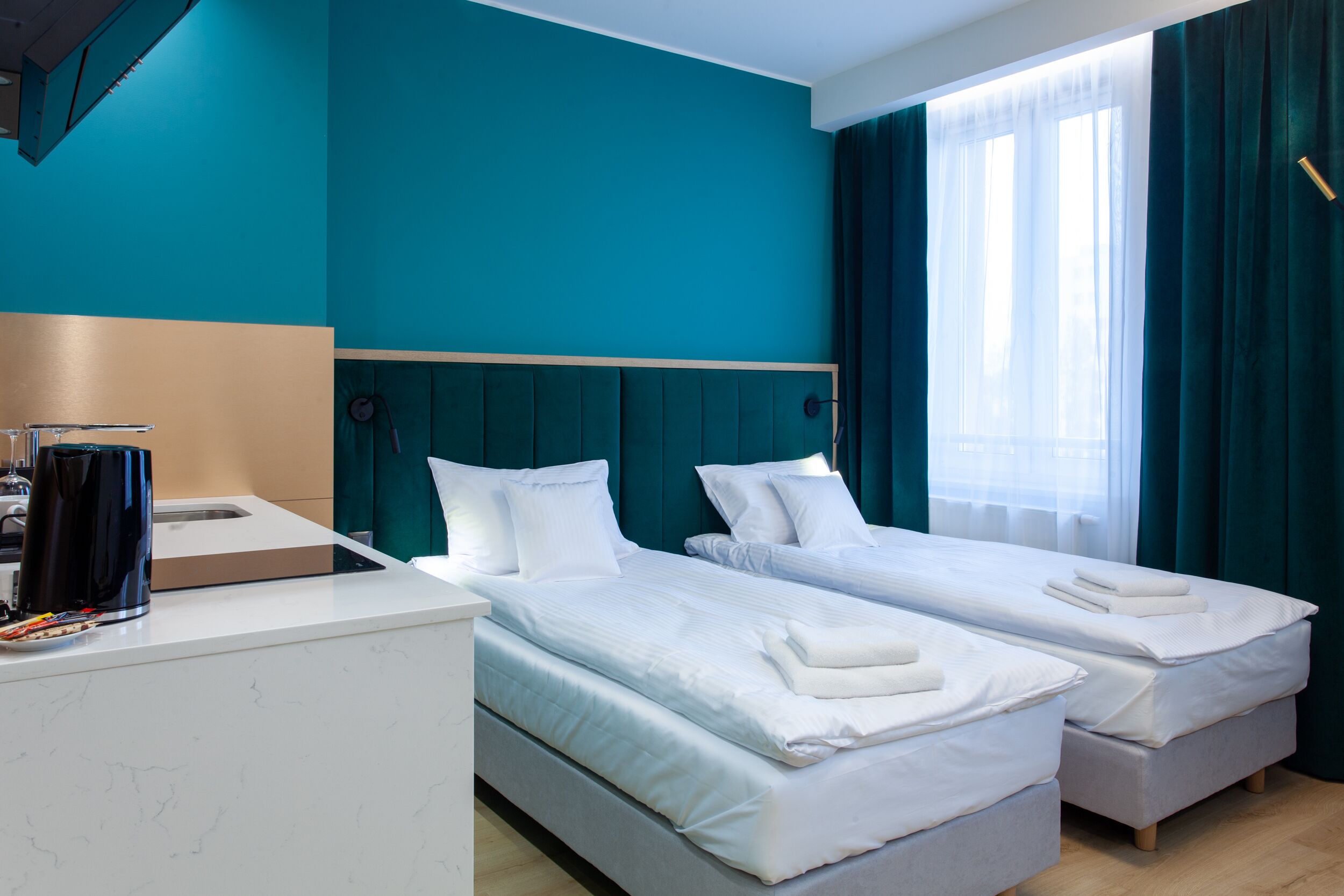 Ett hotellrum med två sängar, ett skrivbord och ett fönster med gardiner.
