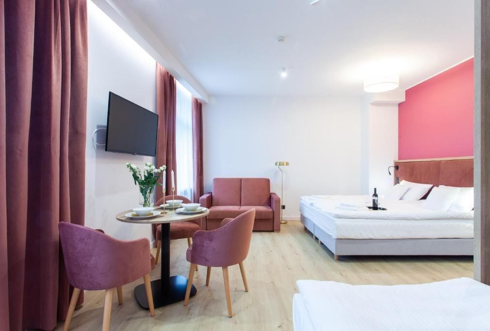 Ett modernt hotellrum med en säng, ett skrivbord med en stol, en soffa och en tv som är monterad på väggen.
