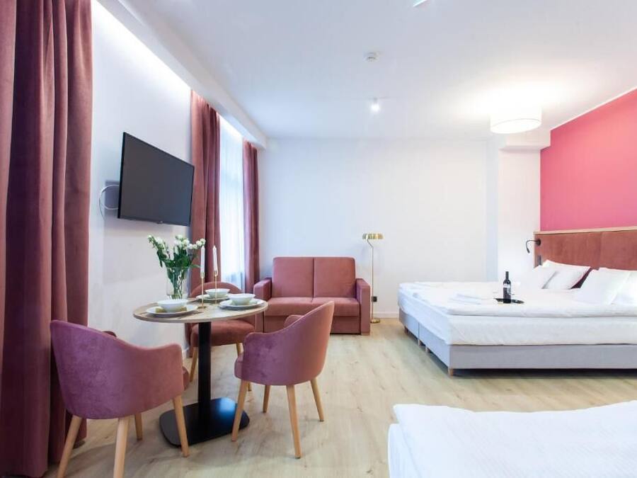 Ett modernt hotellrum med en säng, ett skrivbord med en stol, en soffa och en tv som är monterad på väggen.