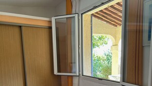 A bedroom with a bed, a wooden wardrobe, a window with curtains, and a wooden dresser. - Charming villa 50 m from the sea. Pets allowed (conca)