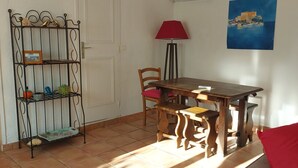 A dining area with a wooden table and chairs, a metal shelf with decorative items, a red lamp, and a painting on the wall. - Charming villa 50 m from the sea. Pets allowed (conca)
