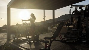 A gym with exercise equipment and a view of the sunset.