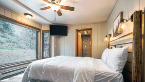 A bedroom with a bed, a ceiling fan, a TV, and a large window. - Hot Tub, Ski Wolf Creek, Fish San Juan River Village (Pagosa Springs)