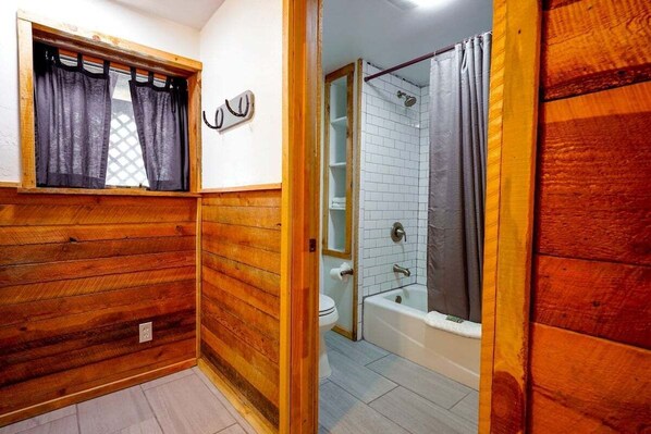 A wooden-paneled bathroom with a window, a toilet, and a bathtub. - Hot Tub, Ski Wolf Creek, Fish San Juan River Village (Pagosa Springs)