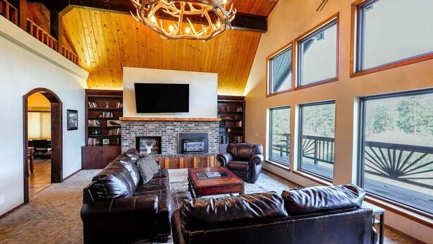 A spacious living room with a large fireplace, leather furniture, and a television mounted on the wall. - Hot Tub, Ski Wolf Creek, Fish San Juan River Village (Pagosa Springs)