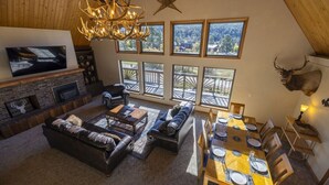 A spacious living room with a fireplace, leather sofas, a dining area with a wooden table set for four, and large windows offering a view of the outdoors. - Hot Tub, Ski Wolf Creek, Fish San Juan River Village (Pagosa Springs)