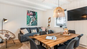 Una sala de estar moderna con una mesa de comedor de madera, sofás grises y un cuadro grande en la pared.