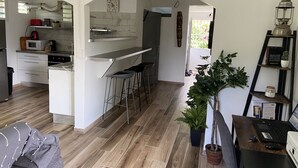 Eine moderne Küche mit Kochinsel, Barhocker und einem Essbereich mit Laptop und Pflanze.