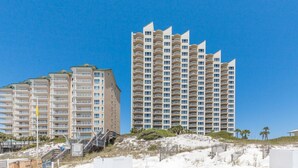 Ein Strandhotel mit mehreren Hochhäusern, einem Sandstrand und blauem Himmel.