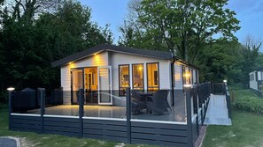 Una casa moderna con un porche acristalado, una zona de estar exterior cubierta y un jardín cuidado.
