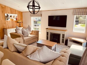 Una sala de estar con sofá, mesa de centro, chimenea, televisor y decoración de pared de madera.