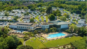 Un ampio campeggio con diversi camper e roulotte, una piscina e un edificio centrale con tetto a cupola.