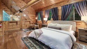 A cozy wooden cabin bedroom with a large bed, a nightstand, and a window with curtains. - Secluded|5 Min to Twn|Game Rm|Kid-Friendly Escape (Pigeon Forge)