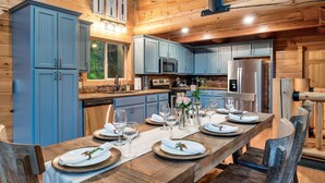 A wooden cabin interior with a dining table set for six, kitchen cabinets, a microwave, and a refrigerator. - Secluded|5 Min to Twn|Game Rm|Kid-Friendly Escape (Pigeon Forge)