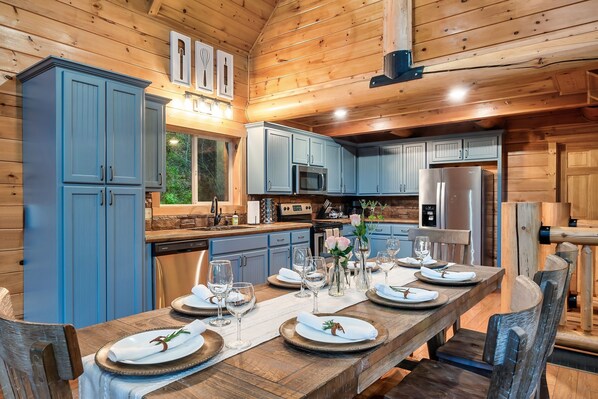 A wooden cabin interior with a dining table set for six, kitchen cabinets, a microwave, and a refrigerator. - Secluded|5 Min to Twn|Game Rm|Kid-Friendly Escape (Pigeon Forge)