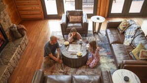 A cozy living room with a stone fireplace, leather sofas, and a coffee table with board games. - Secluded|5 Min to Twn|Game Rm|Kid-Friendly Escape (Pigeon Forge)