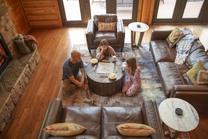 Una sala de estar acogedora con chimenea de piedra, sofás de cuero y una mesa de centro con juegos de mesa.