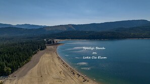 Escape to a serene lakeside setting with a wide sandy beach and forested hills views.