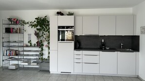 Una cocina moderna con armarios blancos, horno integrado y encimera negra.