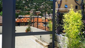 A balcony with a view of a hillside town, a potted plant, and a metal frame structure. - The Time Home&Hotel (Santa Margherita Ligure)