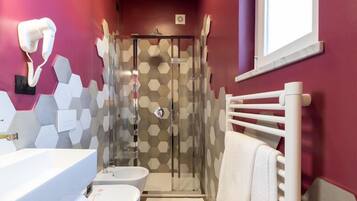 A bathroom with a white sink, a toilet, a shower with a glass door, and a towel rack.