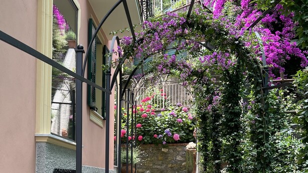 A narrow alleyway with a pink building, a metal staircase, and purple flowers. - The Time Home&Hotel (Santa Margherita Ligure)