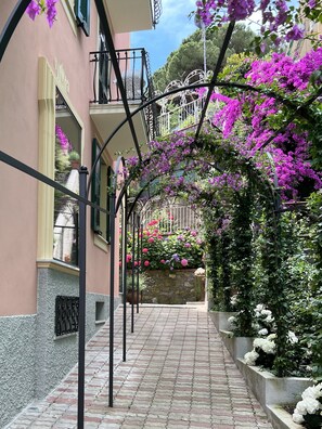A narrow alleyway with a pink building, a metal staircase, and purple flowers. - The Time Home&Hotel (Santa Margherita Ligure)