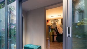 A modern interior with a glass door leading to a room. A teal bench is visible in the foreground. - The Time Home&Hotel (Santa Margherita Ligure)