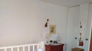 Une chambre à coucher comprenant un lit, une table de chevet, une commode, un miroir et une porte.
