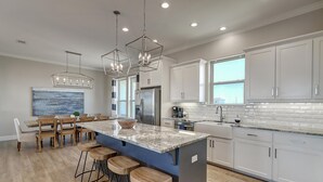 A modern kitchen with a central island, bar stools, and pendant lighting. - Secluded beachfront subdivision with a boardwalk to the beach, private pool! (Port Aransas)