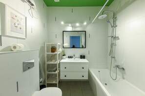 Een moderne badkamer met een wit wastafelmeubel, spiegel en douche. Er staan planken met toiletartikelen en een toilet is zichtbaar.