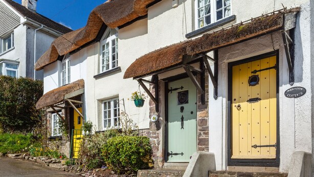 A traditional white building with a thatched roof and a yellow door.