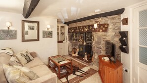 A cozy living room with a stone fireplace, a sofa, a wooden cabinet, and wall-mounted artwork.