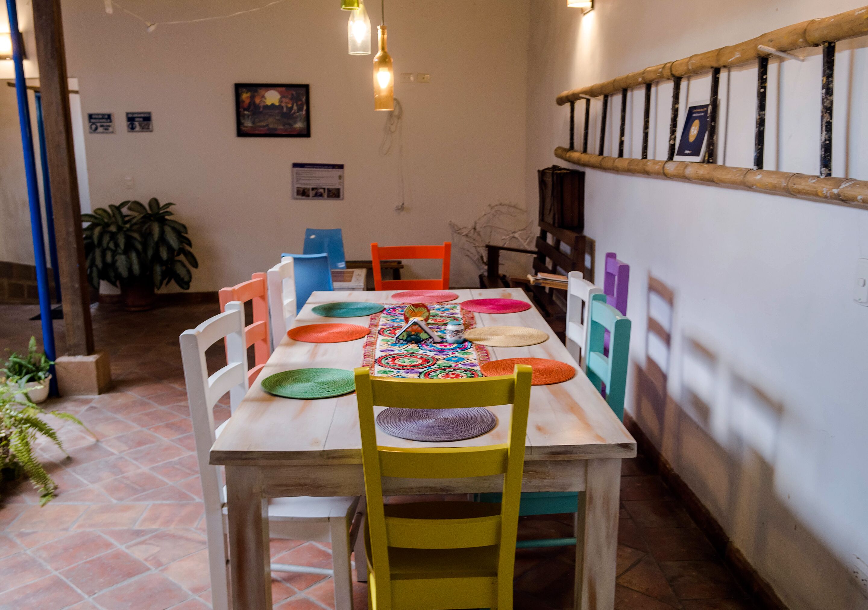 Un comedor con una mesa de madera, individuales coloridos y sillas.