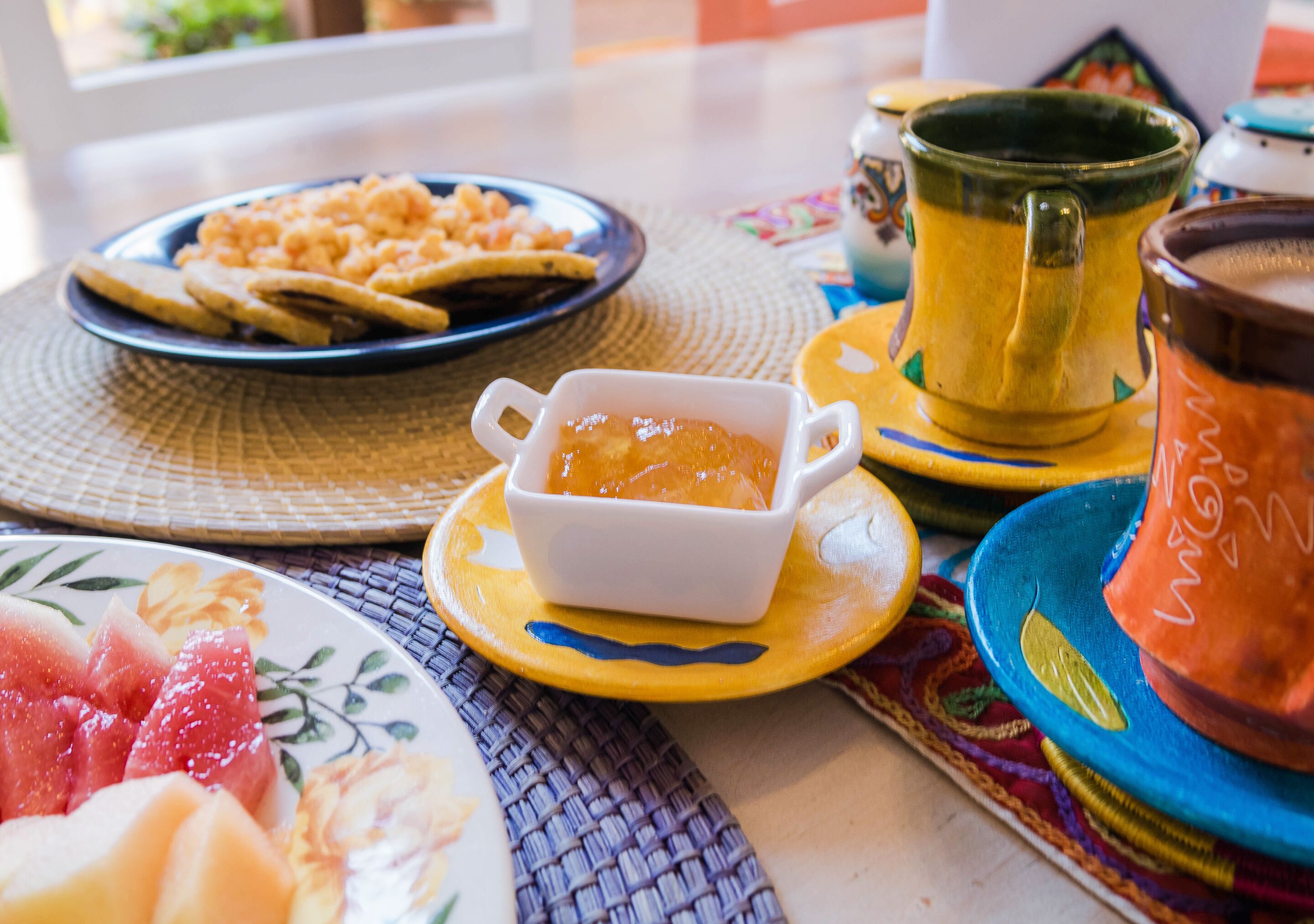 Una mesa con platos de comida, un taz ón de sopa y una tetera.