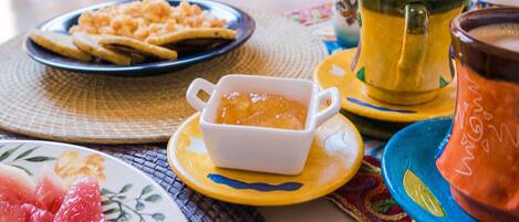 A table with plates of food, a bowl of soup, and a teapot.