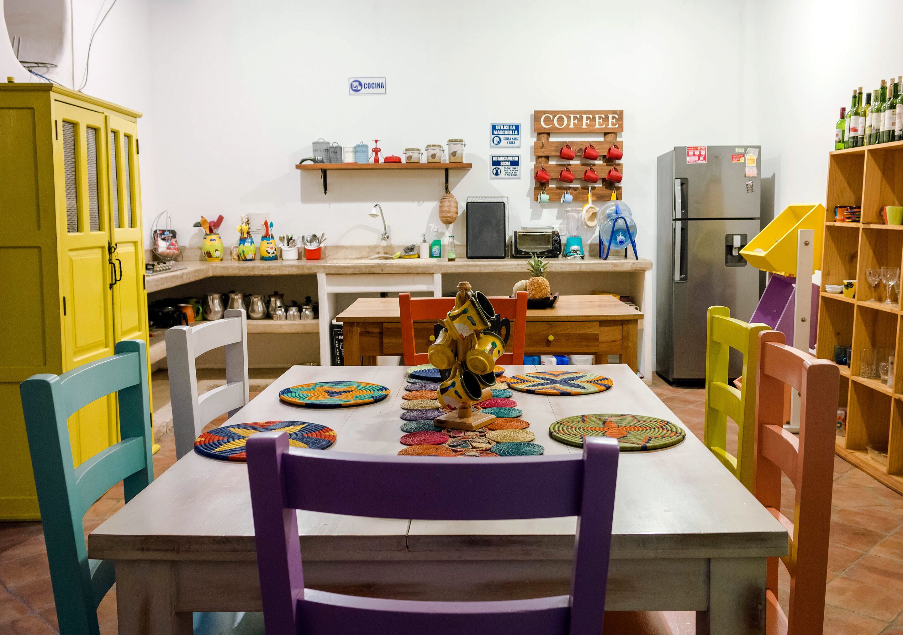 A kitchen with a dining table, chairs, and various kitchen appliances.