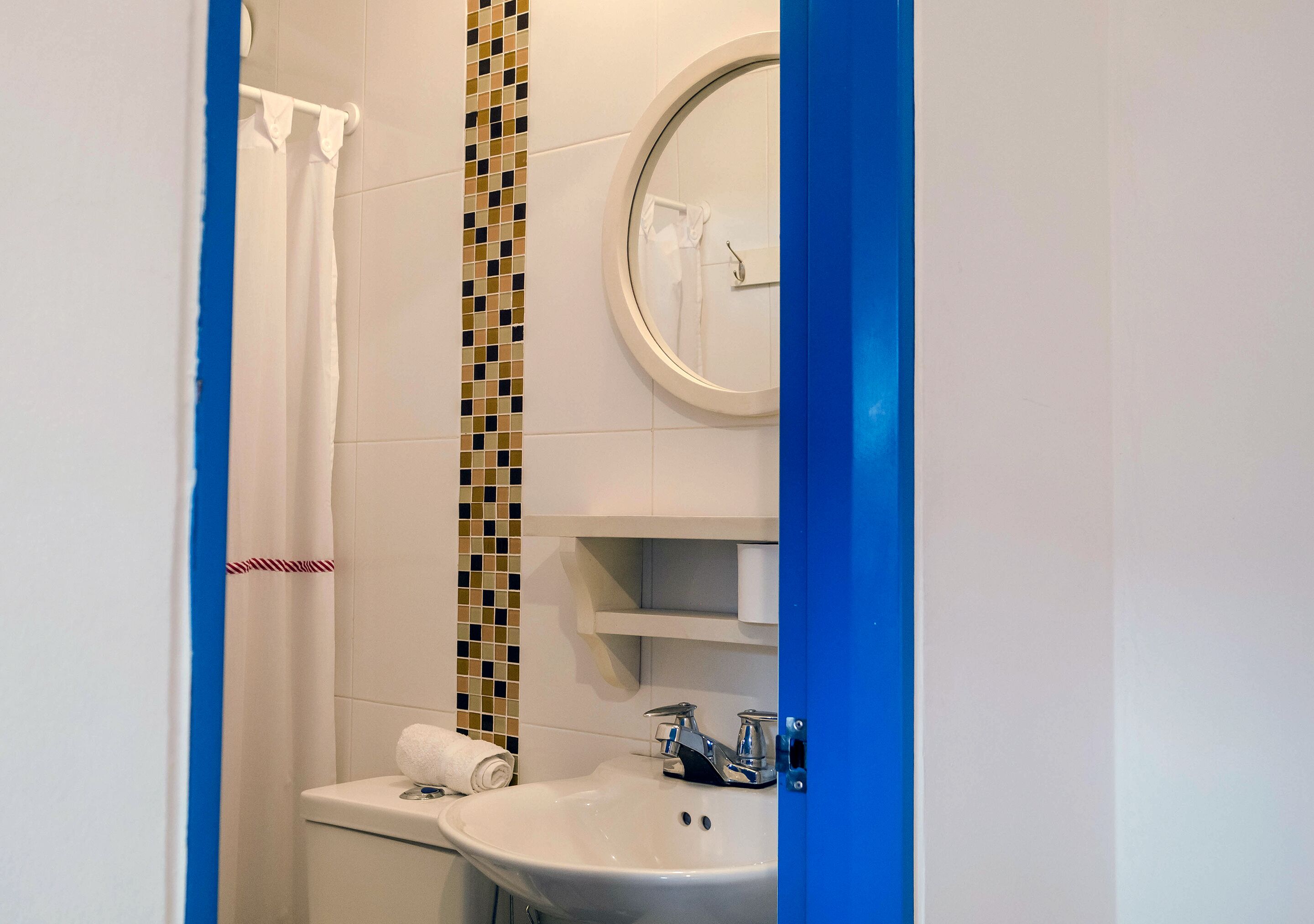 Un baño con lavamanos blanco, un espejo y cortina de ducha.