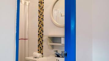 Un baño con lavamanos blanco, un espejo y cortina de ducha.