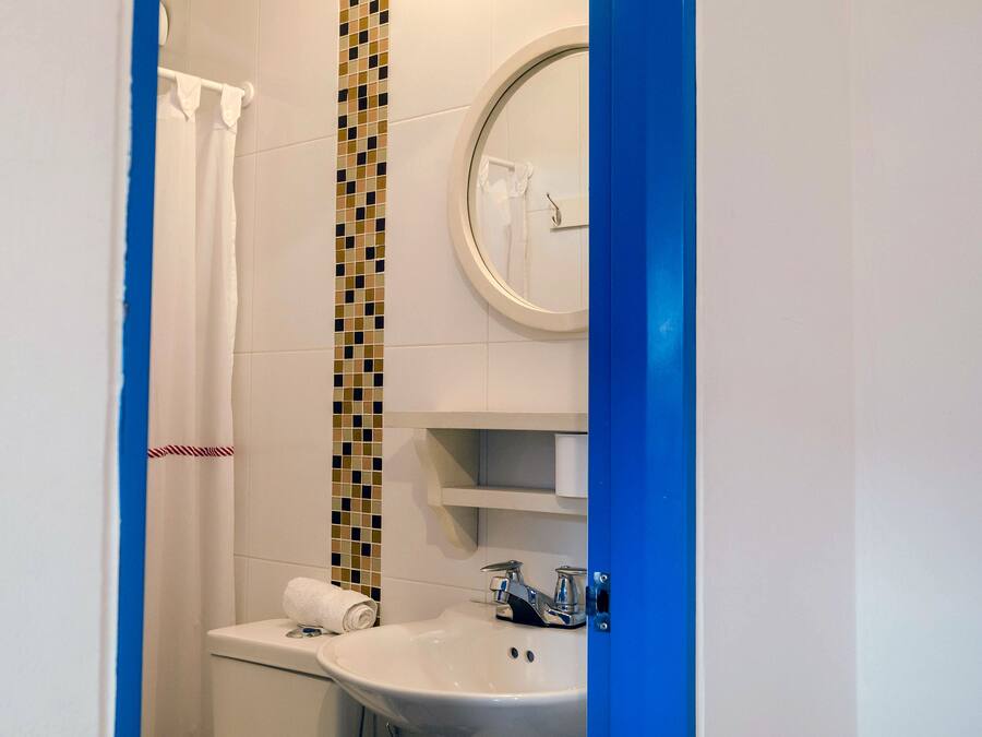 Un baño con lavamanos blanco, un espejo y cortina de ducha.