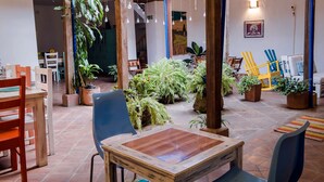 Un espacio interior acogedor con una mesa de madera, sillas y plantas en macetas.